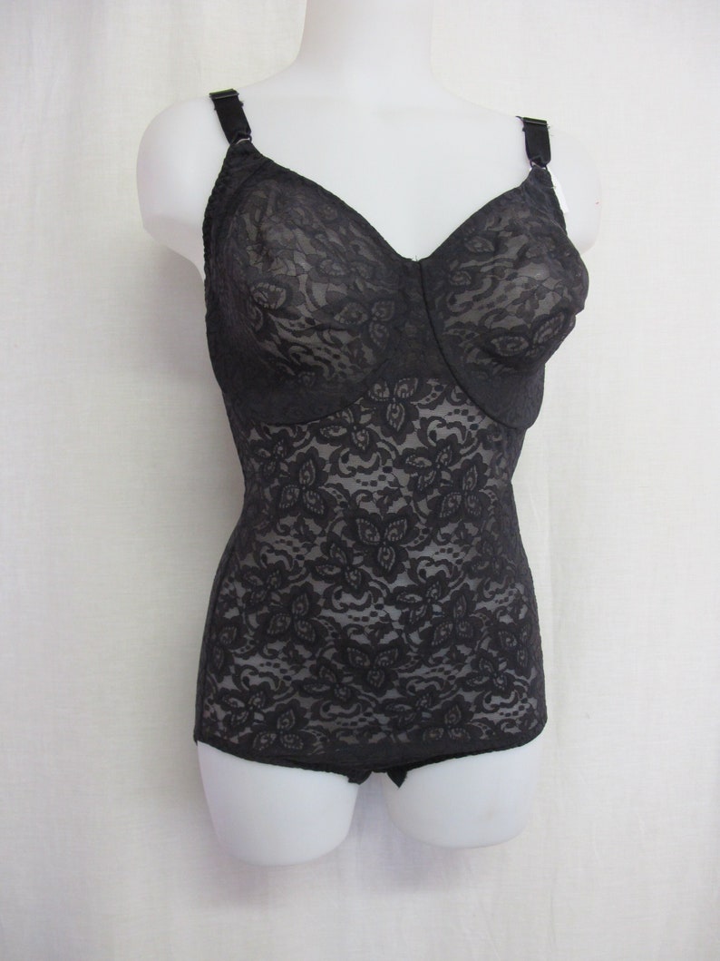 May include: Black lace body suit with adjustable straps. The suit has a floral pattern and is made of a sheer fabric.