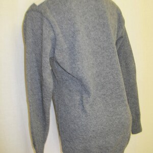 May include: A gray long-sleeved sweater with a white trim around the neckline.