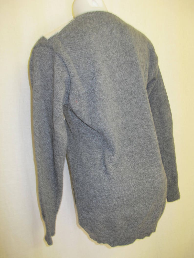 May include: A gray long-sleeved sweater with a white trim around the neckline.