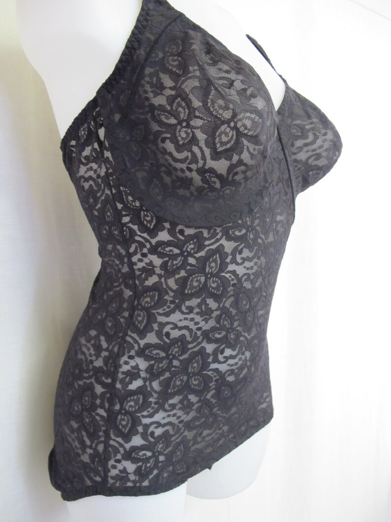 May include: Black lace bodysuit with a floral pattern. The bodysuit has a low neckline and adjustable straps.