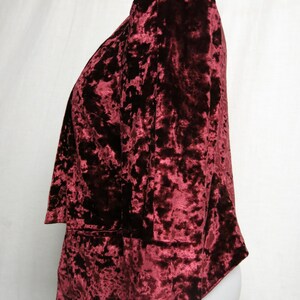 May include: A maroon crushed velvet blazer with long sleeves and a slightly open front.