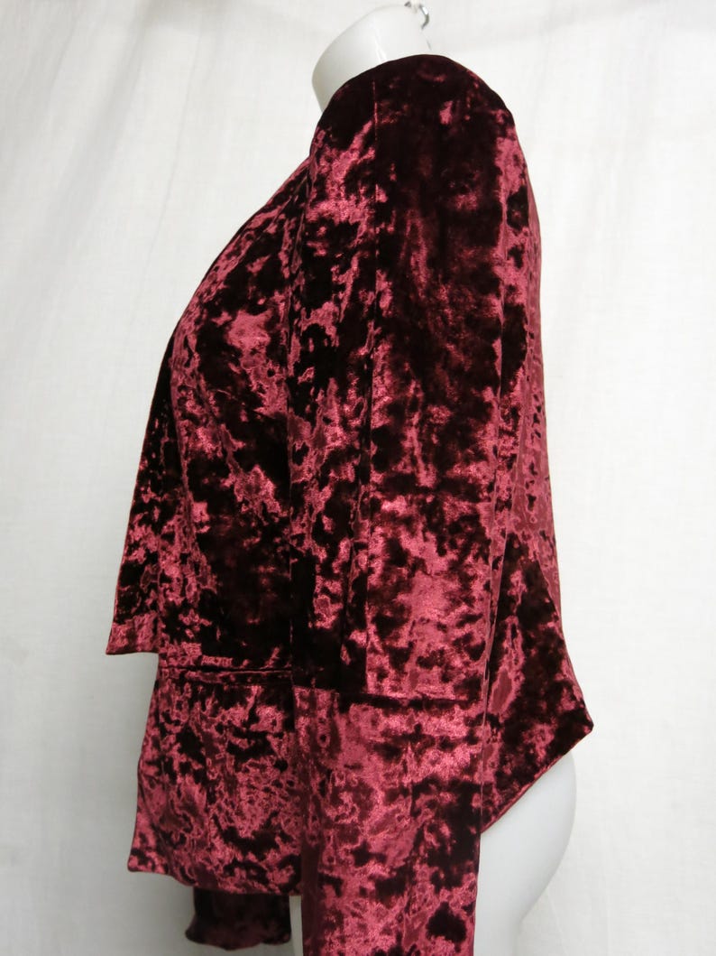 May include: A maroon crushed velvet blazer with long sleeves and a slightly open front.