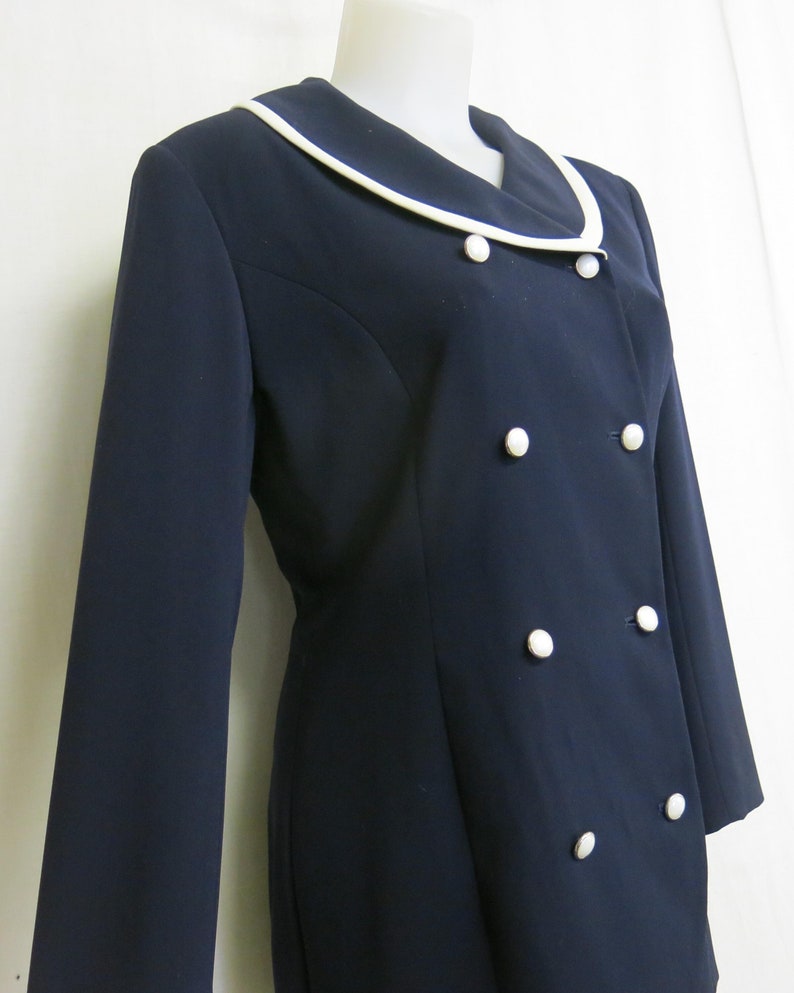 May include: A navy blue blazer with a white collar and white buttons. The blazer has a double-breasted closure.