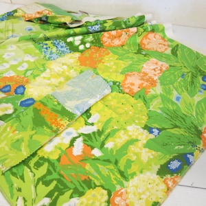 Könnte beinhalten: Grüner Stoff mit einem Blumendruck mit orangefarbenen, gelben und blauen Blumen. Der Stoff hat einen Vintage-Look und wäre perfekt für eine Vielzahl von Nähprojekten.