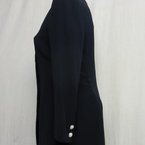 May include: A navy blue blazer with long sleeves and two white buttons on each cuff.