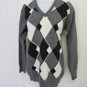 May include: Gray sweater with a black and white diamond pattern.