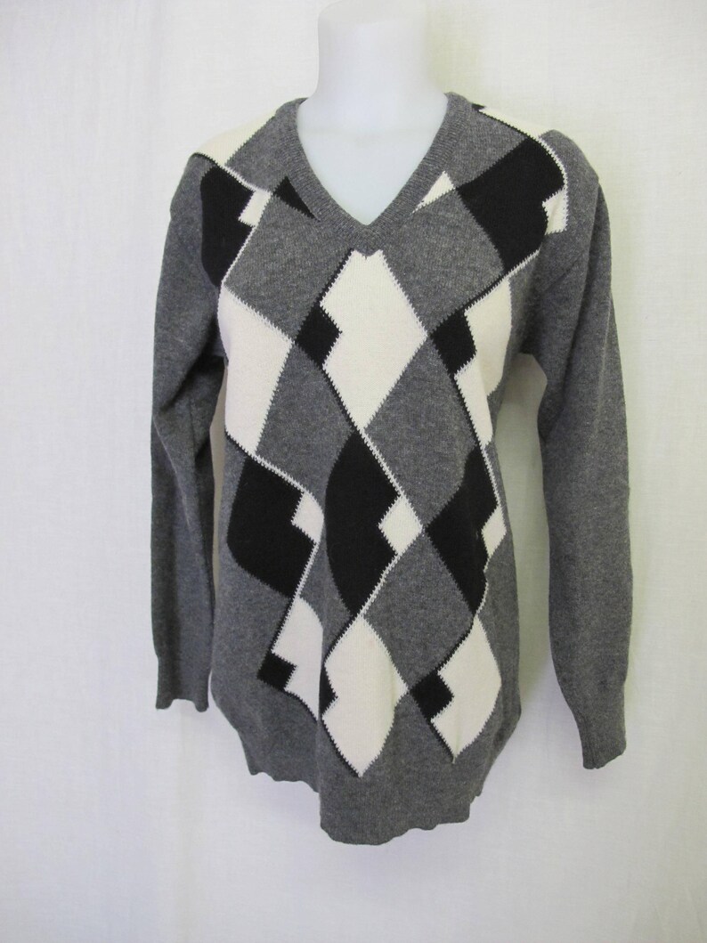 May include: Gray sweater with a black and white diamond pattern.