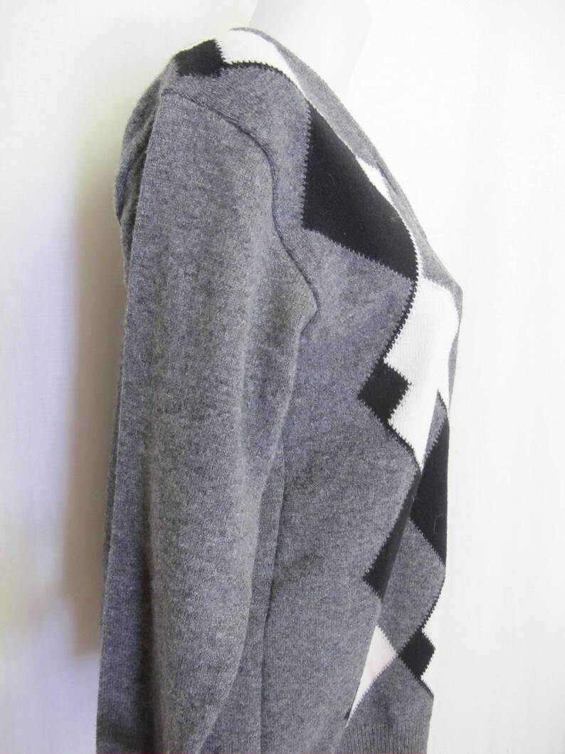 May include: A gray sweater with a black and white diamond pattern.