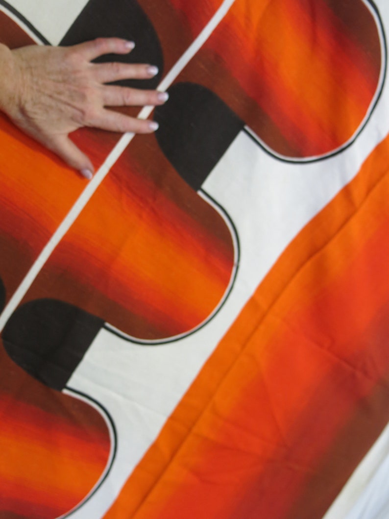 May include: Abstract fabric with a white background and orange, brown, and black geometric shapes. The fabric has a gradient effect, with the orange fading to brown.