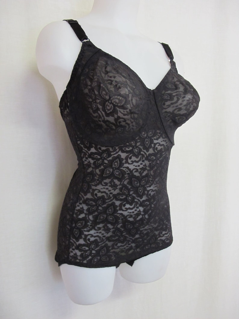 May include: Black lace body suit with adjustable straps. The suit has a floral pattern and is made of a sheer fabric.