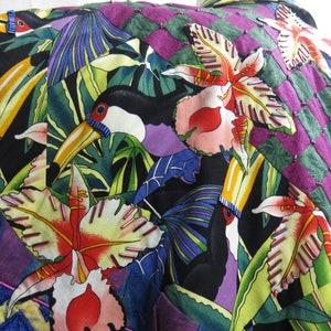 May include: A colorful fabric with a tropical print featuring toucans, orchids, and palm leaves. The fabric is a patchwork of different colors and patterns, including purple, green, blue, and yellow.
