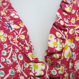 May include: Close-up of a pink fabric with a white floral and star pattern. The fabric has a ruffled edge.