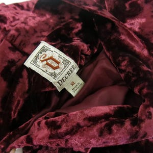May include: A burgundy velvet robe with a large "DECREE" label, featuring a stylised "D" logo and the size "XL". Made in Vietnam.