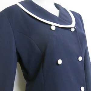 May include: A navy blue blazer with a white collar and white buttons. The blazer has a double-breasted closure.