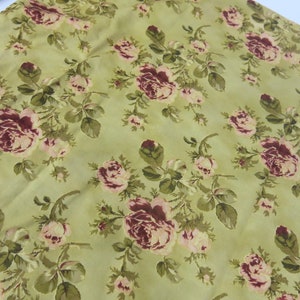 May include: A green fabric with a floral pattern featuring pink and burgundy roses. The fabric has a subtle sheen and a soft texture.