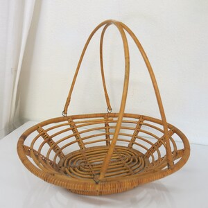 May include: A natural woven wicker basket with two handles. The basket is oval shaped and has a woven pattern.