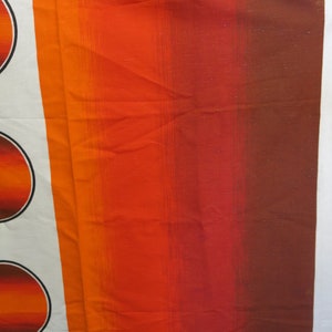 May include: A close-up of a fabric with a striped pattern in shades of orange, red, and brown. The fabric has a subtle sheen and a textured surface.