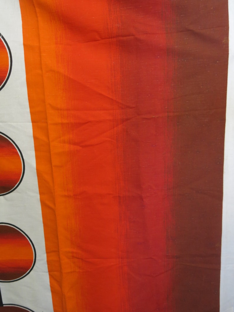 May include: A close-up of a fabric with a striped pattern in shades of orange, red, and brown. The fabric has a subtle sheen and a textured surface.