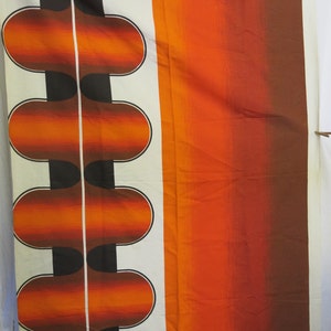 May include: Orange and brown fabric with a repeating pattern of rounded shapes. The fabric has a white background with a vertical line down the centre.