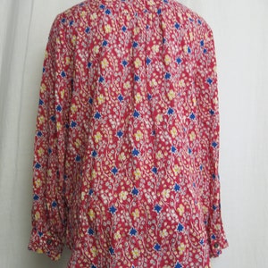 May include: A red, long-sleeved blouse with a floral print featuring blue stars and yellow flowers.