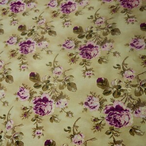 May include: A beige fabric with a repeating pattern of pink and purple roses. The roses are surrounded by green leaves and stems.
