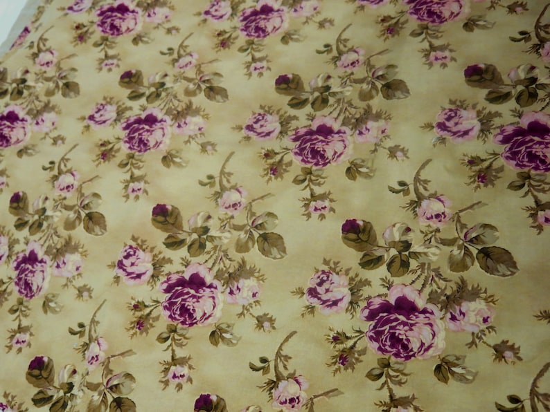 May include: A beige fabric with a repeating pattern of pink and purple roses. The roses are surrounded by green leaves and stems.