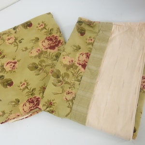 May include: Two fabric panels with a floral pattern. The panels are green with a red and white floral design. One panel has a solid beige backing.