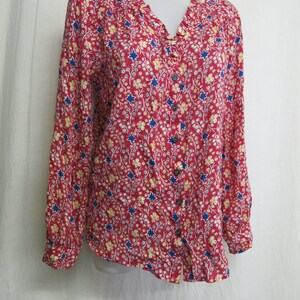May include: A red long-sleeved button-up shirt with a floral print featuring blue stars and yellow flowers.
