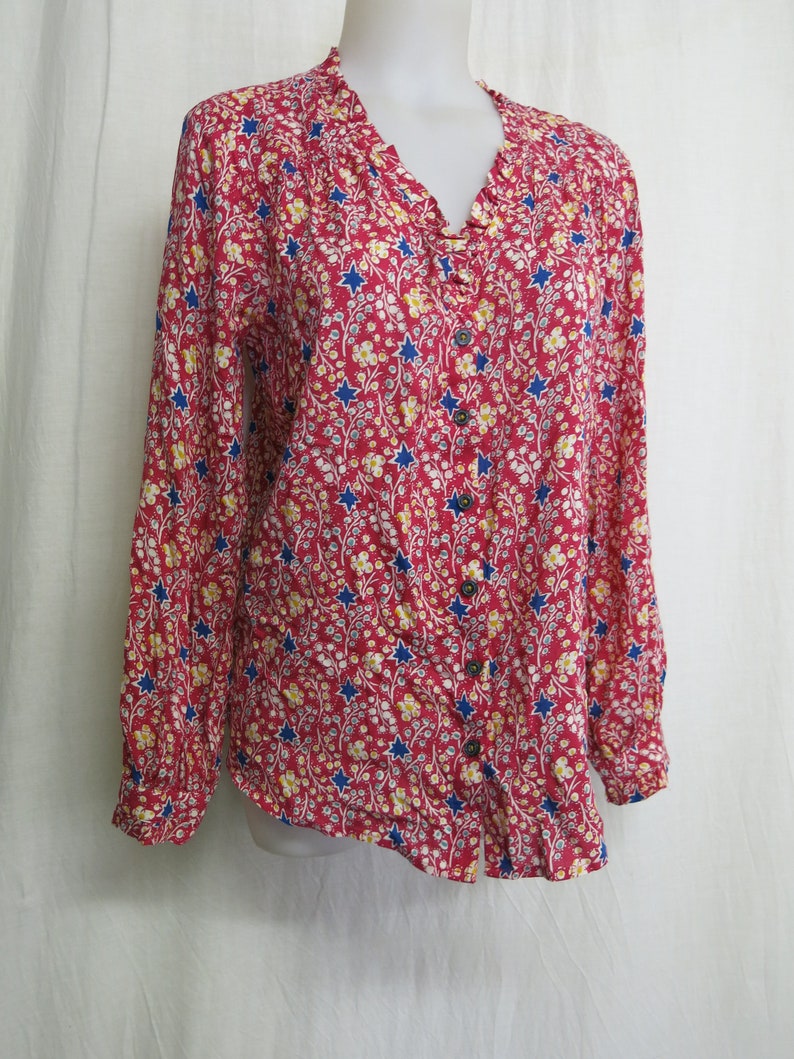 May include: A red long-sleeved button-up shirt with a floral print featuring blue stars and yellow flowers.