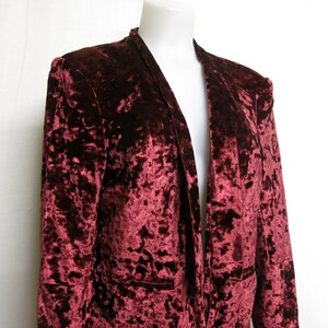 May include: A maroon velvet blazer with a long, open front and a crushed velvet texture.
