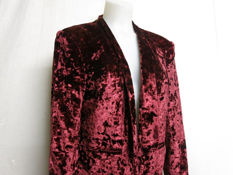 May include: A maroon velvet blazer with a long, open front and a crushed velvet texture.