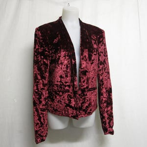 May include: A burgundy velvet blazer with a long, open front and a crushed velvet texture.