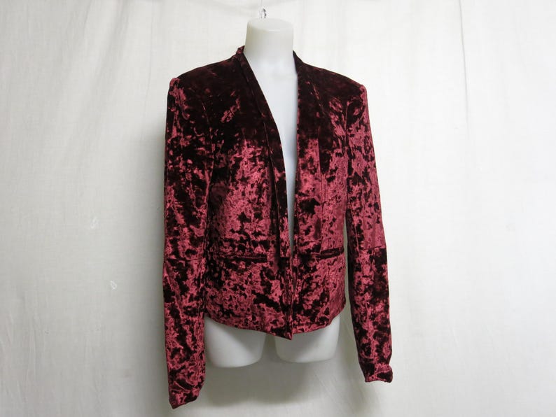 May include: A burgundy velvet blazer with a long, open front and a crushed velvet texture.