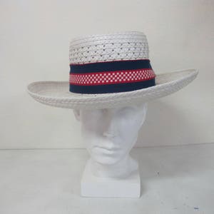 Puede incluir: Sombrero de paja blanco con una banda a cuadros azul y roja. El sombrero est&aacute; en una cabeza de maniqu&iacute; blanca.