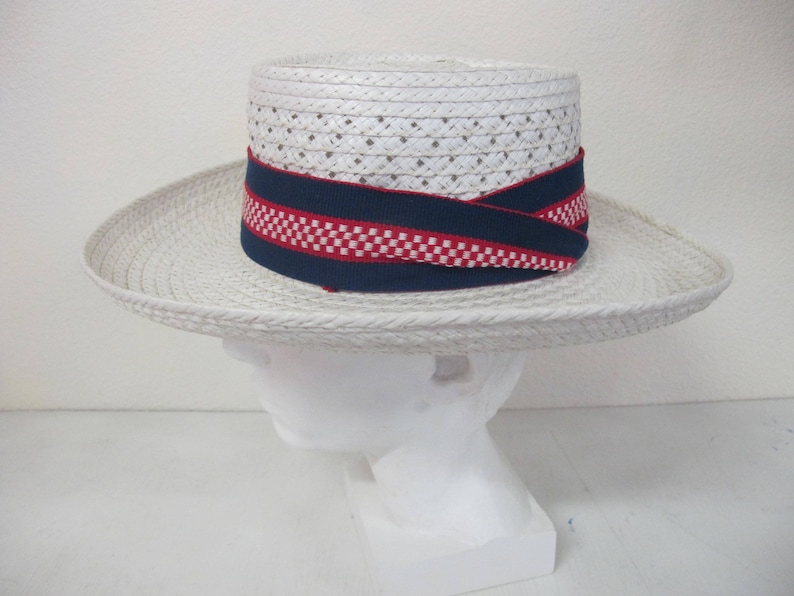 Puede incluir: Sombrero de paja blanco con ala ancha y cinta de list&oacute;n a cuadros azul y rojo.