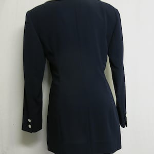 May include: A navy blue blazer with a white collar and cuffs. The blazer has a double-breasted closure and a fitted silhouette.