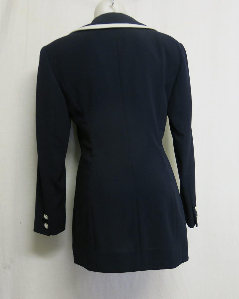 May include: A navy blue blazer with a white collar and cuffs. The blazer has a double-breasted closure and a fitted silhouette.