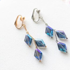 Peut inclure: Une paire de boucles d'oreilles &agrave; clip avec une cha&icirc;ne pendante et trois perles bleu iris&eacute; en forme de diamant.