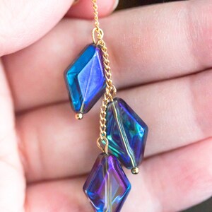 Peut inclure: Une cha&icirc;ne dor&eacute;e avec trois perles de verre en forme de diamant bleu et violet iris&eacute;.