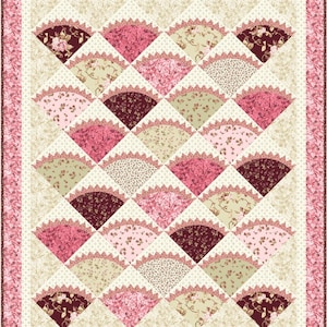 May include: A quilt with a diamond pattern featuring pink, brown, and cream fabric with floral designs. The quilt is edged with a pink floral border.