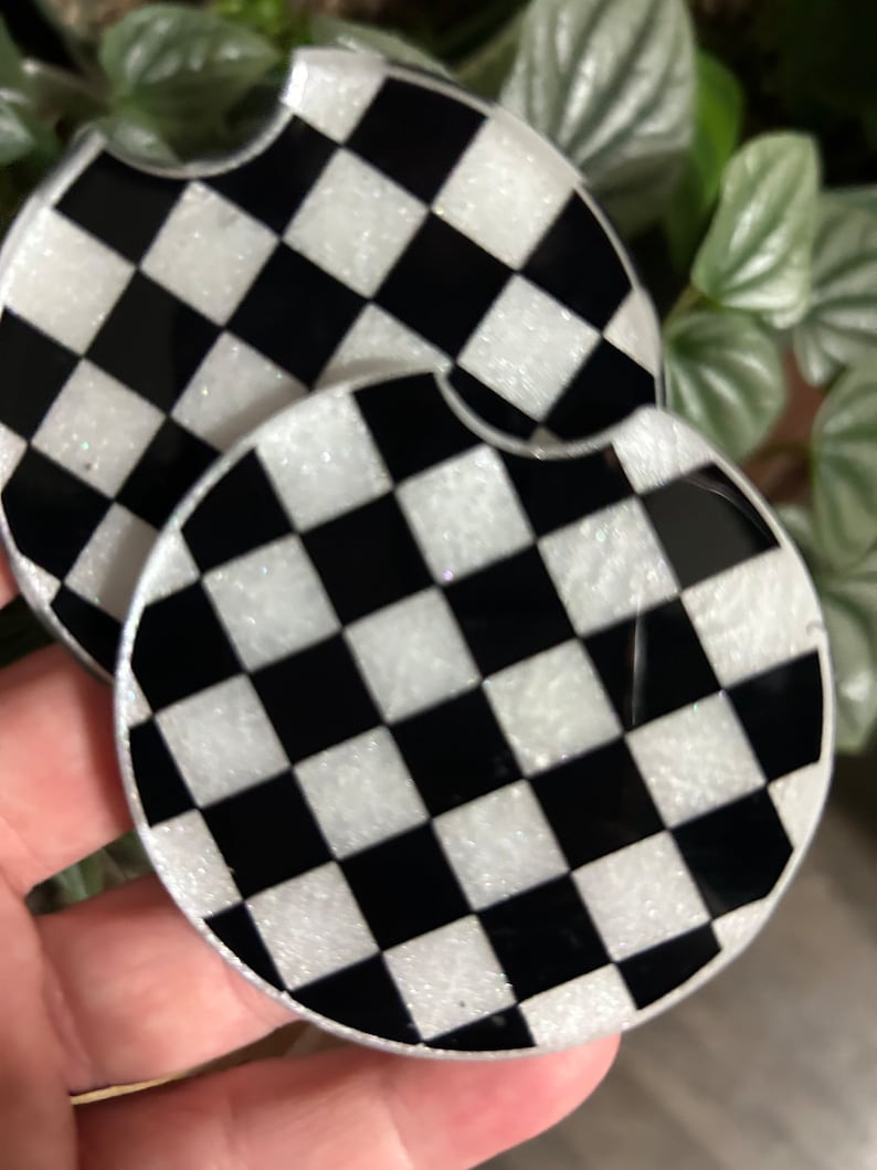 May include: Two black and white checkered round coasters with a glittery finish.