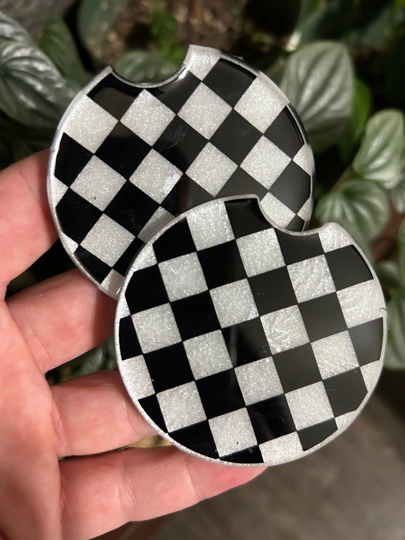 May include: Two black and white checkered round coasters with a glittery finish