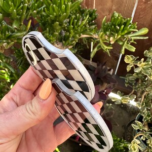 May include: Two black and white checkered coasters with a silver rim. The coasters are made of a hard, durable material and are perfect for protecting surfaces from spills and scratches.