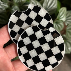 May include: Two black and white checkered round coasters with a glittery finish.