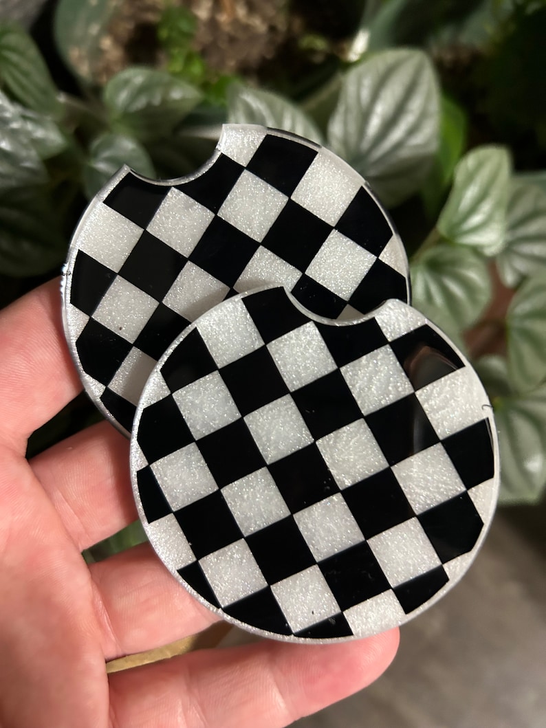 May include: Two black and white checkered round coasters with a glittery finish.