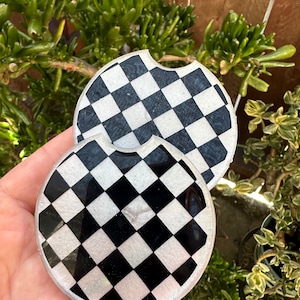 May include: Two black and white checkered round coasters with a glossy finish.