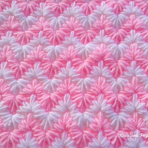 Puede incluir: Primer plano de una tela de crochet rosa y blanca con un patrón de estrella repetido. La tela está hecha con hilo suave y tiene una textura delicada.