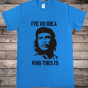 May include: A blue t-shirt with a black silhouette of a man with a beard and a beret. The text "I've no idea who this is" is printed on the shirt.