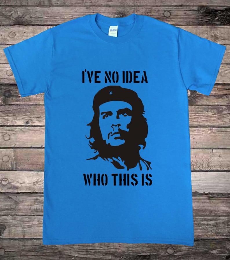 May include: A blue t-shirt with a black silhouette of a man with a beard and a beret. The text "I've no idea who this is" is printed on the shirt.