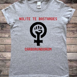 May include: Gray t-shirt with a black feminist symbol and the text "NOLITE TE BASTARDES CARBORUNDORUM" in red.